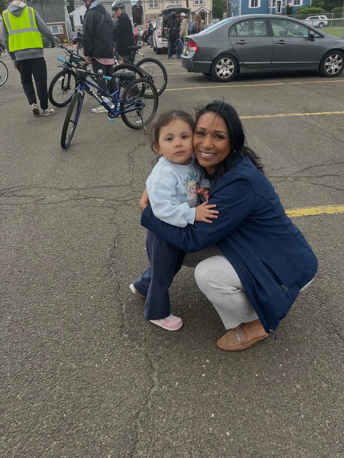 Assemblywoman Carmen Morales sharing an outdoor embrace with a young child, with bicycles behind them